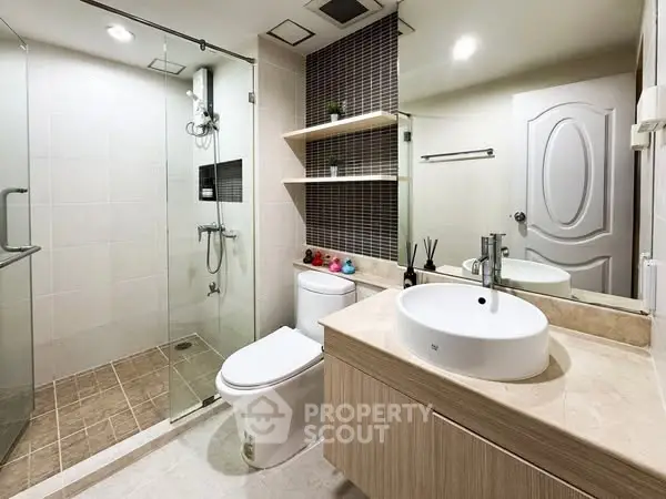 Modern bathroom with glass shower and sleek vanity in contemporary home.