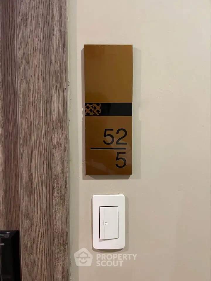 Modern apartment door with stylish room number plaque and light switch