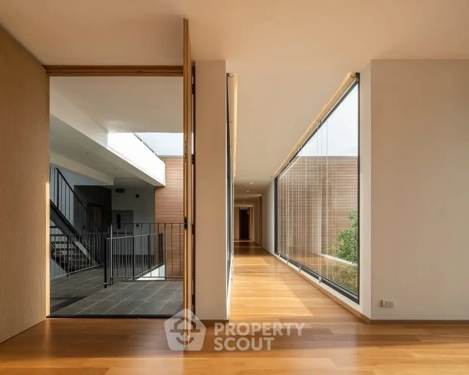 Modern corridor with wooden flooring and large glass windows in luxury building.