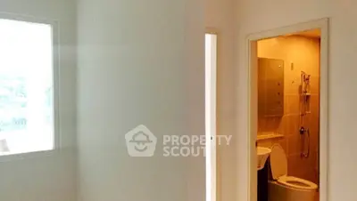 Modern apartment interior with a glimpse of a bathroom and bright natural light.