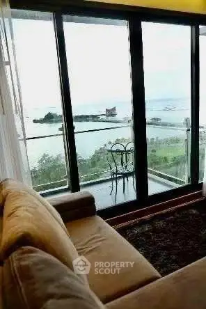 Stunning living room with panoramic ocean view from large glass doors and cozy seating area.