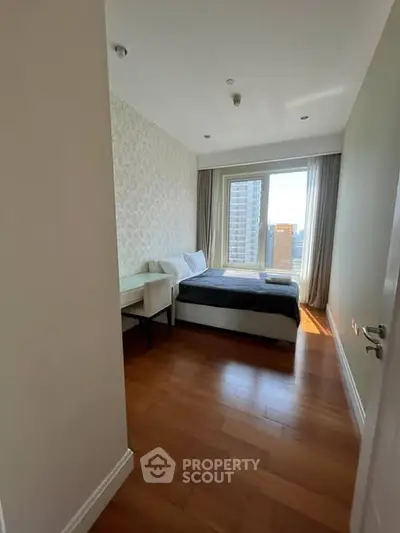Modern bedroom with city view, featuring hardwood floors and elegant decor.