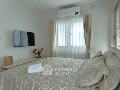 Cozy bedroom with elegant decor, featuring a mounted TV and air conditioning for ultimate comfort.