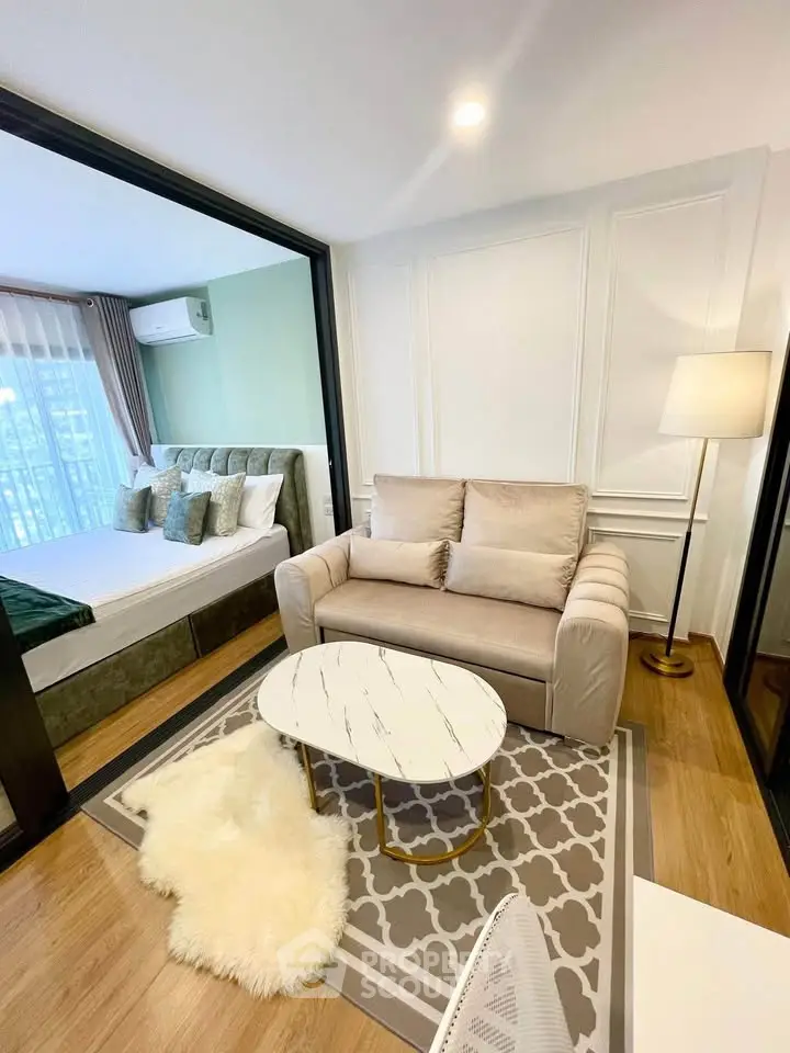 Modern living room with cozy sofa, stylish coffee table, and view into elegant bedroom with plush bedding.