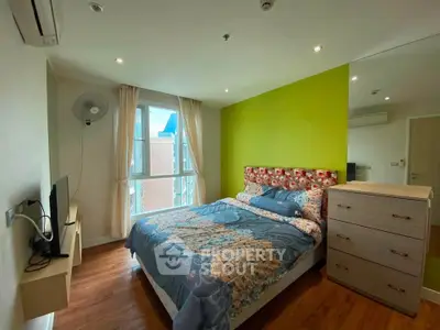 Cozy bedroom with vibrant green accent wall and modern furnishings in a stylish apartment.