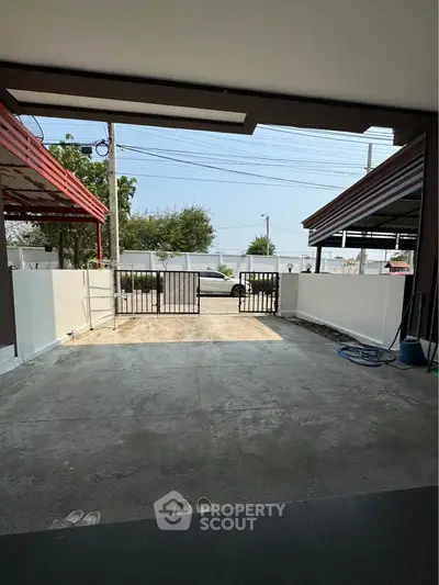 Spacious residential driveway with gated entrance and covered parking area.