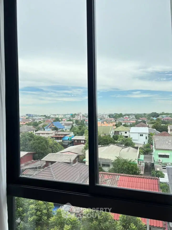Stunning cityscape view from a high-rise window showcasing vibrant rooftops and lush greenery.