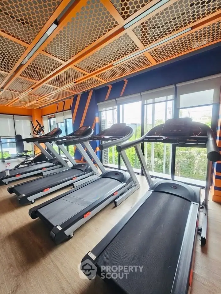 Modern gym with multiple treadmills and large windows offering a bright and airy workout space.