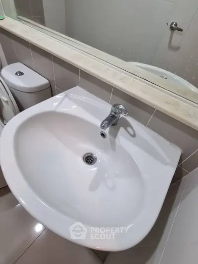 Modern bathroom with sleek white sink and large mirror, perfect for contemporary living.