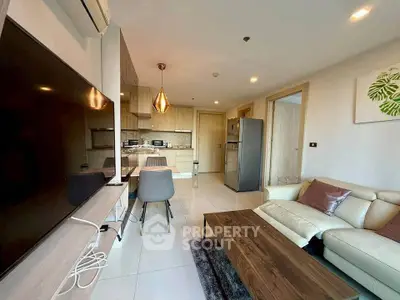 Modern living room with open kitchen, featuring sleek furniture and contemporary design.