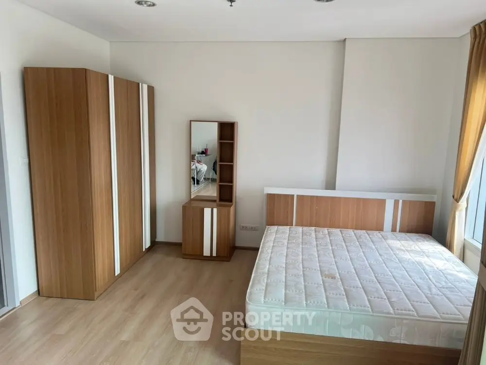 Spacious bedroom with modern wooden furniture and large window for natural light.