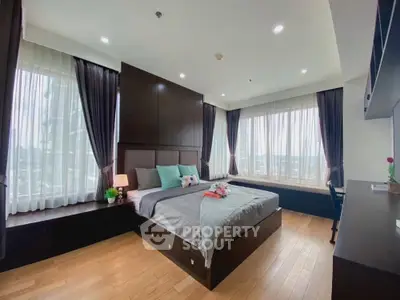Luxurious bedroom with large windows and elegant decor in modern apartment.