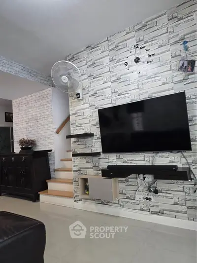 Modern living room with stylish stone accent wall and mounted TV, featuring sleek furniture and elegant decor.