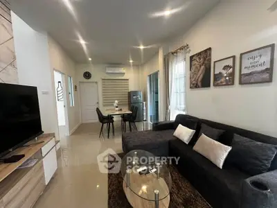 Modern living room with stylish decor and open dining area, featuring a cozy sofa and wall art.