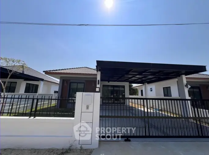 Modern single-story house with sleek design and spacious driveway under clear blue sky.