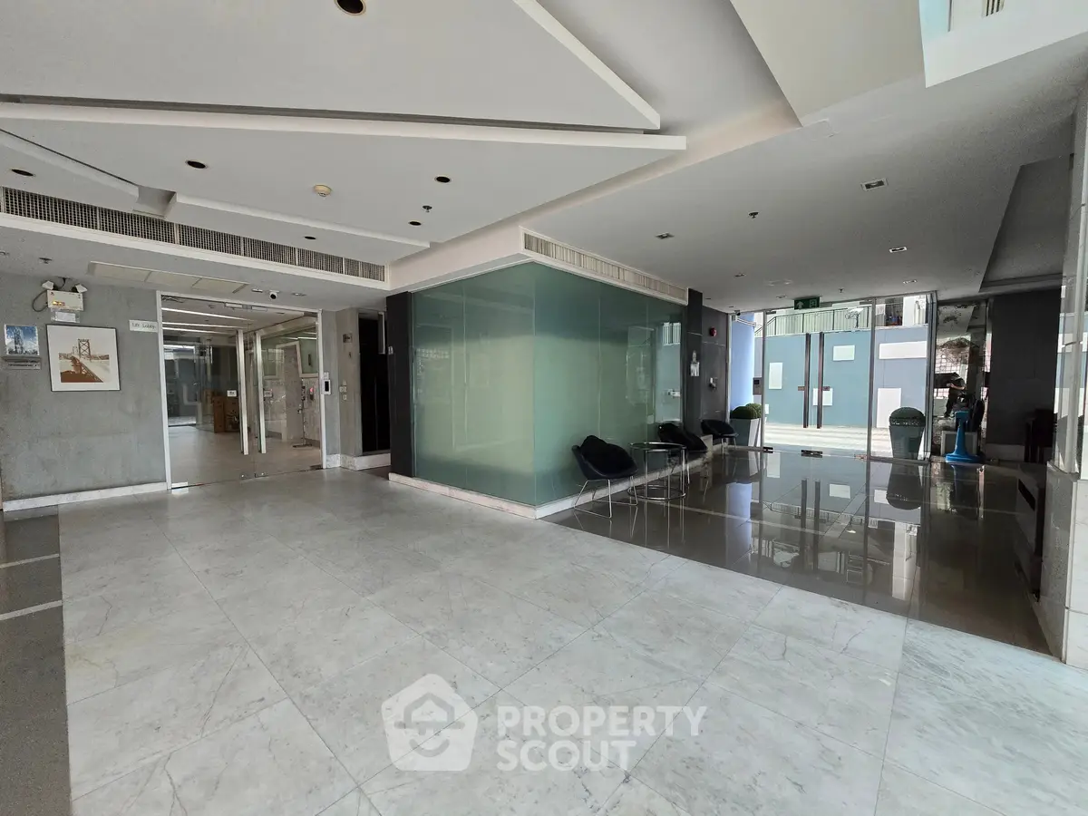 Spacious modern building entrance with sleek marble flooring and glass walls, ideal for luxury living.