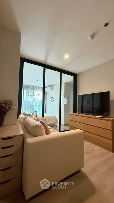 Modern living room with cozy sofa and large TV, featuring a bright balcony view.