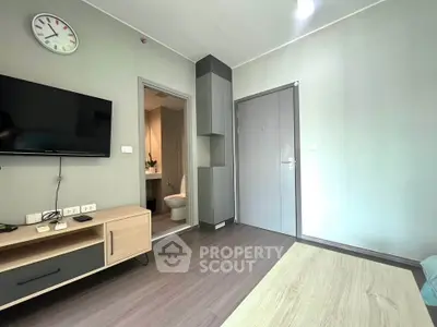 Modern living room with sleek furniture and wall-mounted TV, featuring a glimpse into a stylish bathroom.