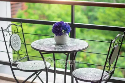Charming balcony with elegant wrought iron furniture and lush green view, perfect for relaxation.