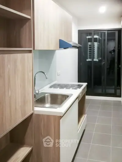 Modern kitchen with sleek cabinetry and glass sliding doors leading to balcony.