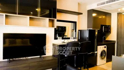 Modern apartment interior with sleek kitchen and living area featuring black appliances and stylish decor.
