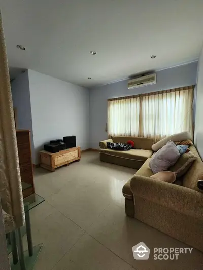 Spacious living room with ample natural light, cozy sofas, air conditioning, and a serene ambiance perfect for relaxation and entertainment.