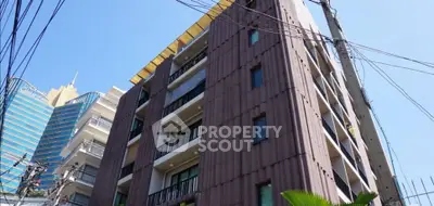 Modern multi-story building with balconies in urban setting, showcasing contemporary architecture.