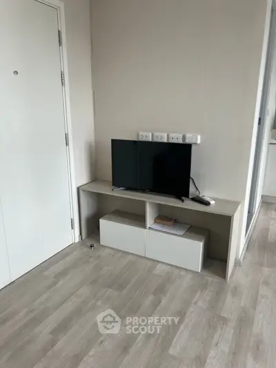 Modern minimalist living room with sleek TV stand and hardwood flooring.