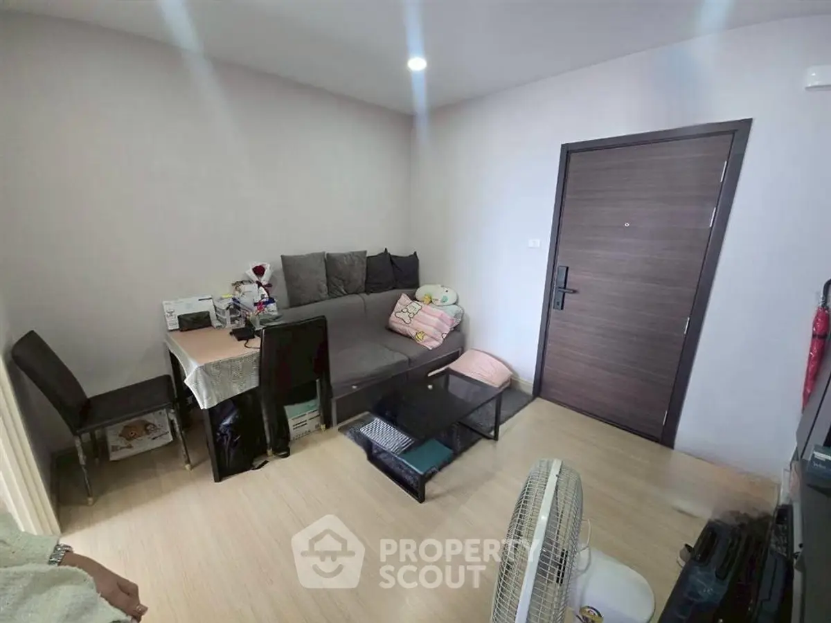 Cozy living room with modern furniture and wooden flooring in a compact apartment.