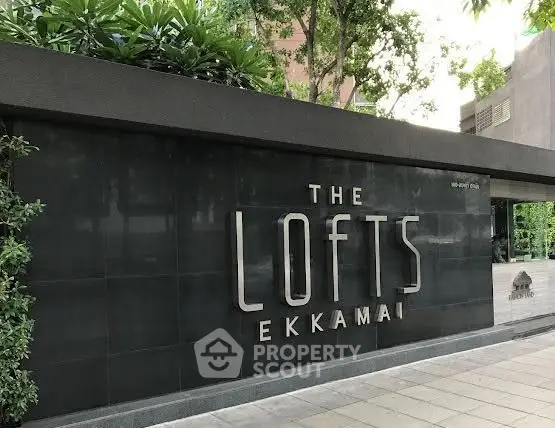 Modern exterior of The Lofts Ekkamai with sleek signage and lush greenery.