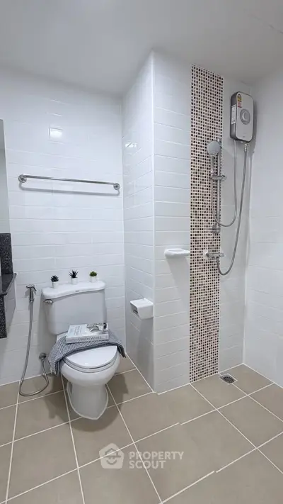 Modern bathroom with sleek white tiles and shower heater, perfect for a contemporary home.