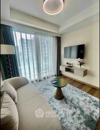 Modern living room with plush sofa, stylish rug, and wall-mounted TV in a bright apartment.