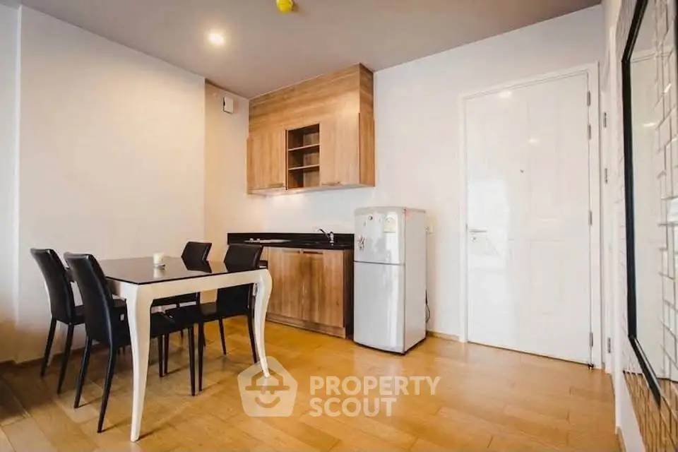 Modern kitchen with dining area, featuring wooden cabinets and sleek black chairs.