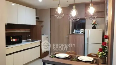 Modern kitchen with dining area, featuring stylish lighting and contemporary appliances.