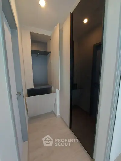 Modern storage space with sleek black and wood cabinetry in a contemporary apartment.