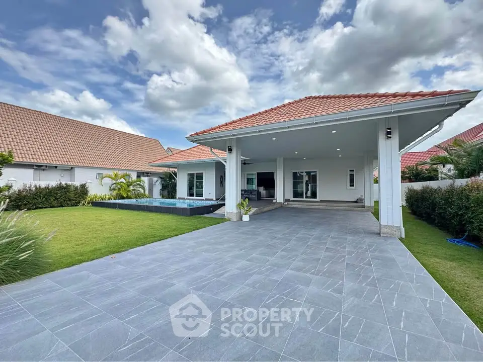 Stunning modern house with spacious driveway and lush green lawn under a vibrant sky.