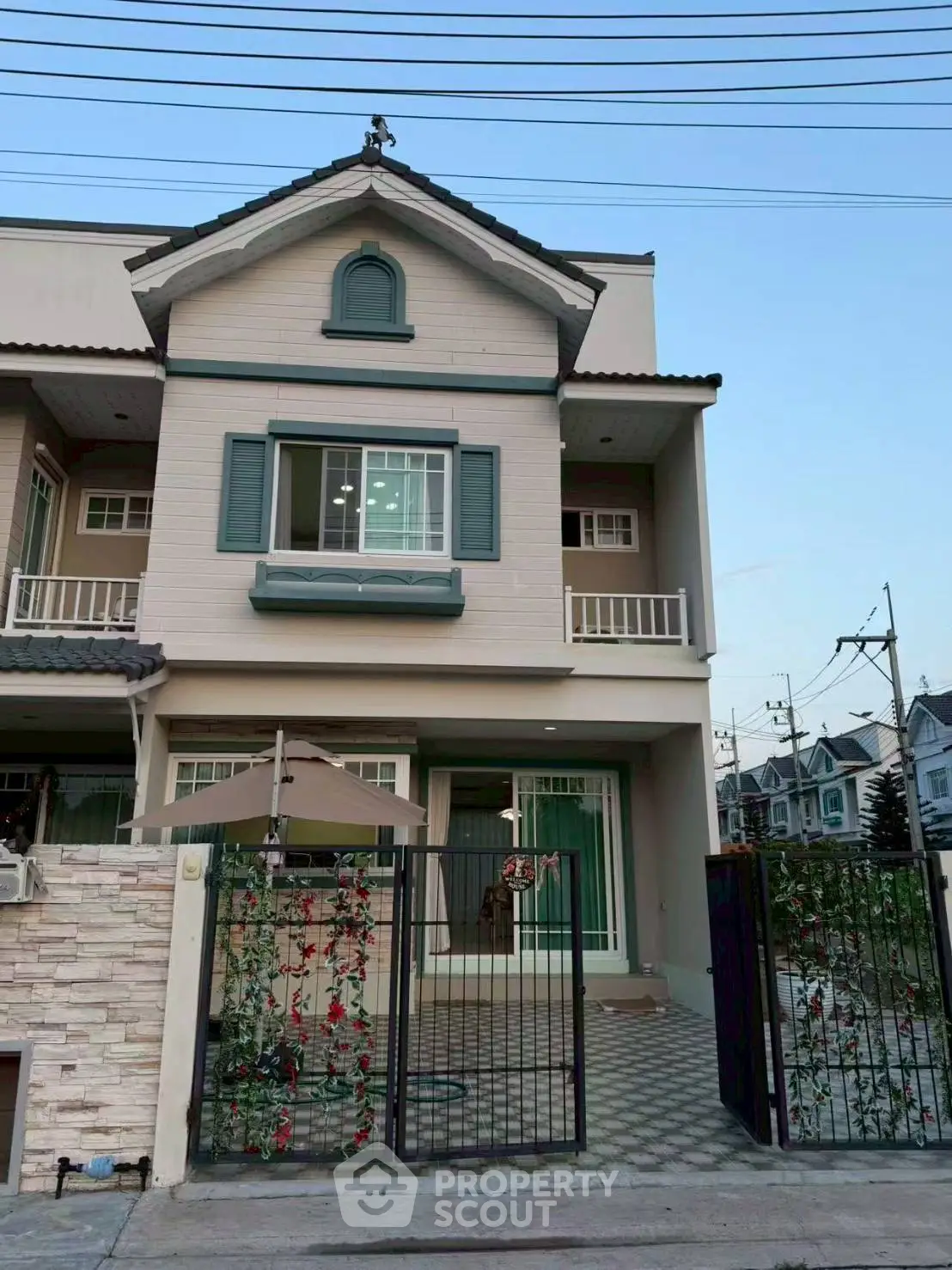 Charming two-story townhouse with balcony and gated entrance in a serene neighborhood.