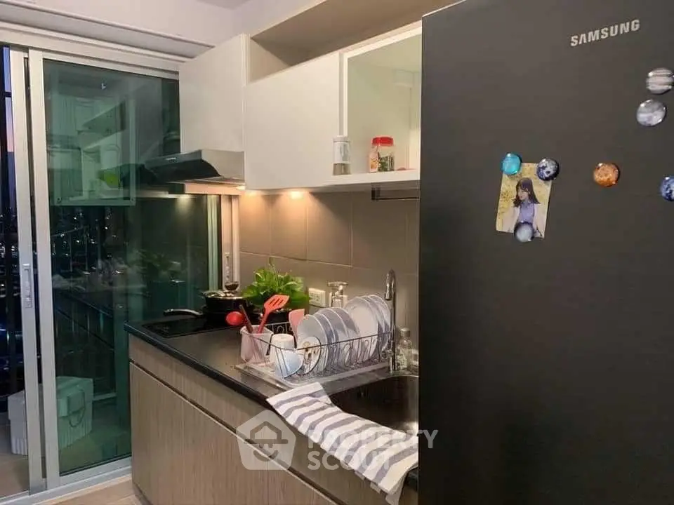 Modern kitchen with sleek black appliances and open layout, featuring a Samsung fridge and stylish decor.