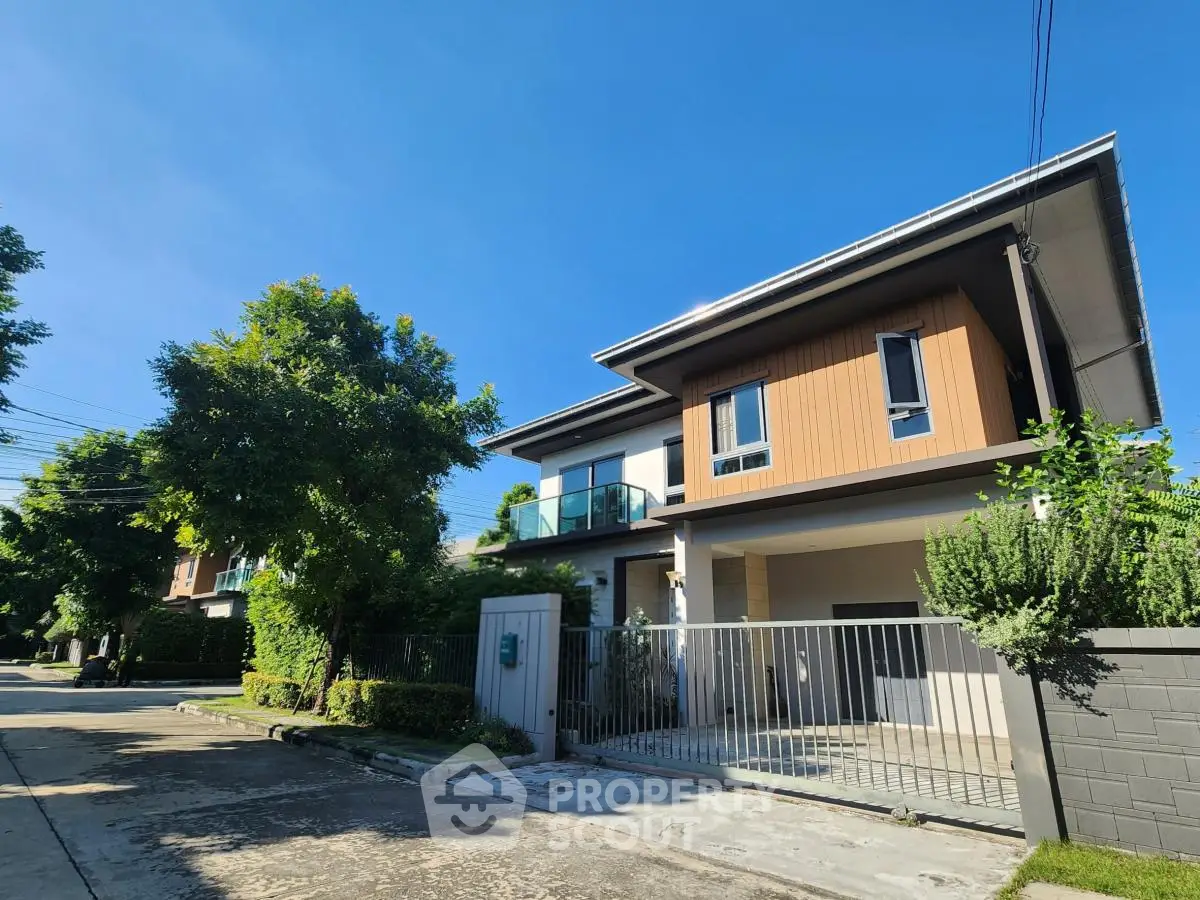 Modern two-story house with sleek design and lush greenery in a serene neighborhood.