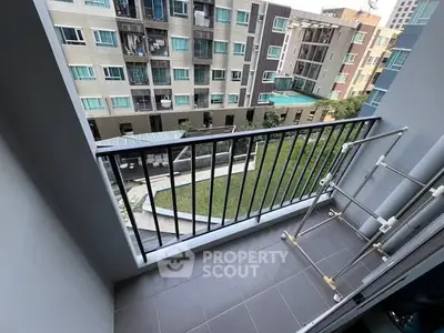 Charming balcony view overlooking modern apartment complex with lush garden area.