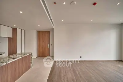 Modern open-plan living room with elegant wooden flooring and stylish kitchen counter.