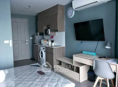 Modern studio apartment with compact kitchen and stylish decor, featuring a wall-mounted TV and air conditioning.