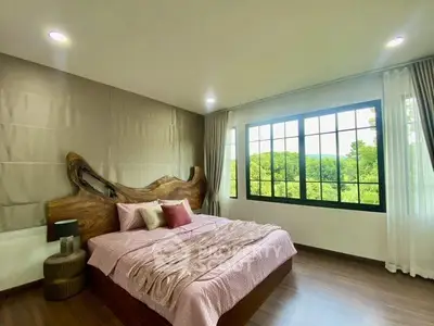 Spacious bedroom with large window offering scenic views and elegant wooden headboard.