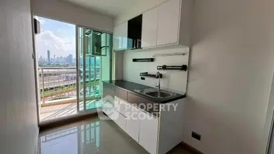 Modern compact kitchen with city view and balcony access in urban apartment