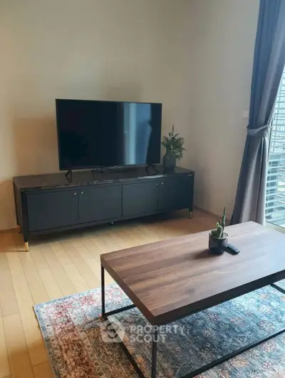Modern living room with sleek TV stand and wooden coffee table, featuring a cozy rug and natural light.