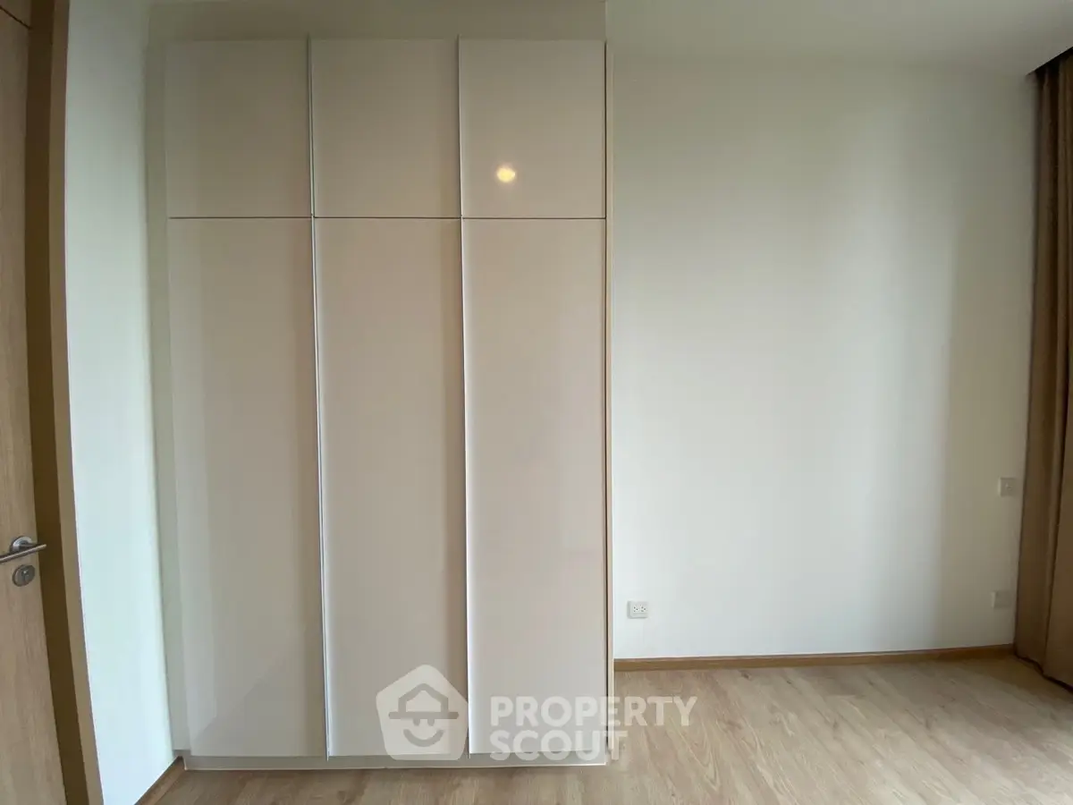 Modern minimalist bedroom with sleek wardrobe and wooden flooring