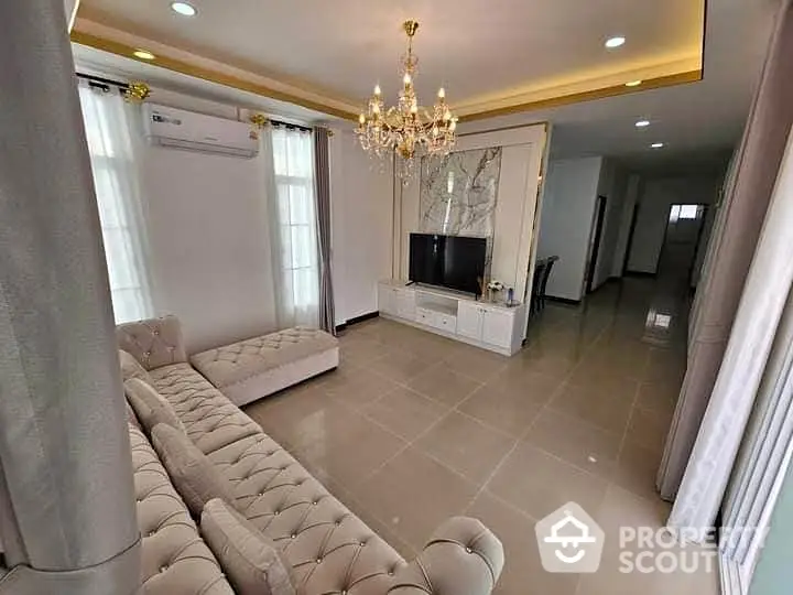 Elegant living room with chandelier and modern decor, featuring a plush sectional sofa and sleek TV unit.