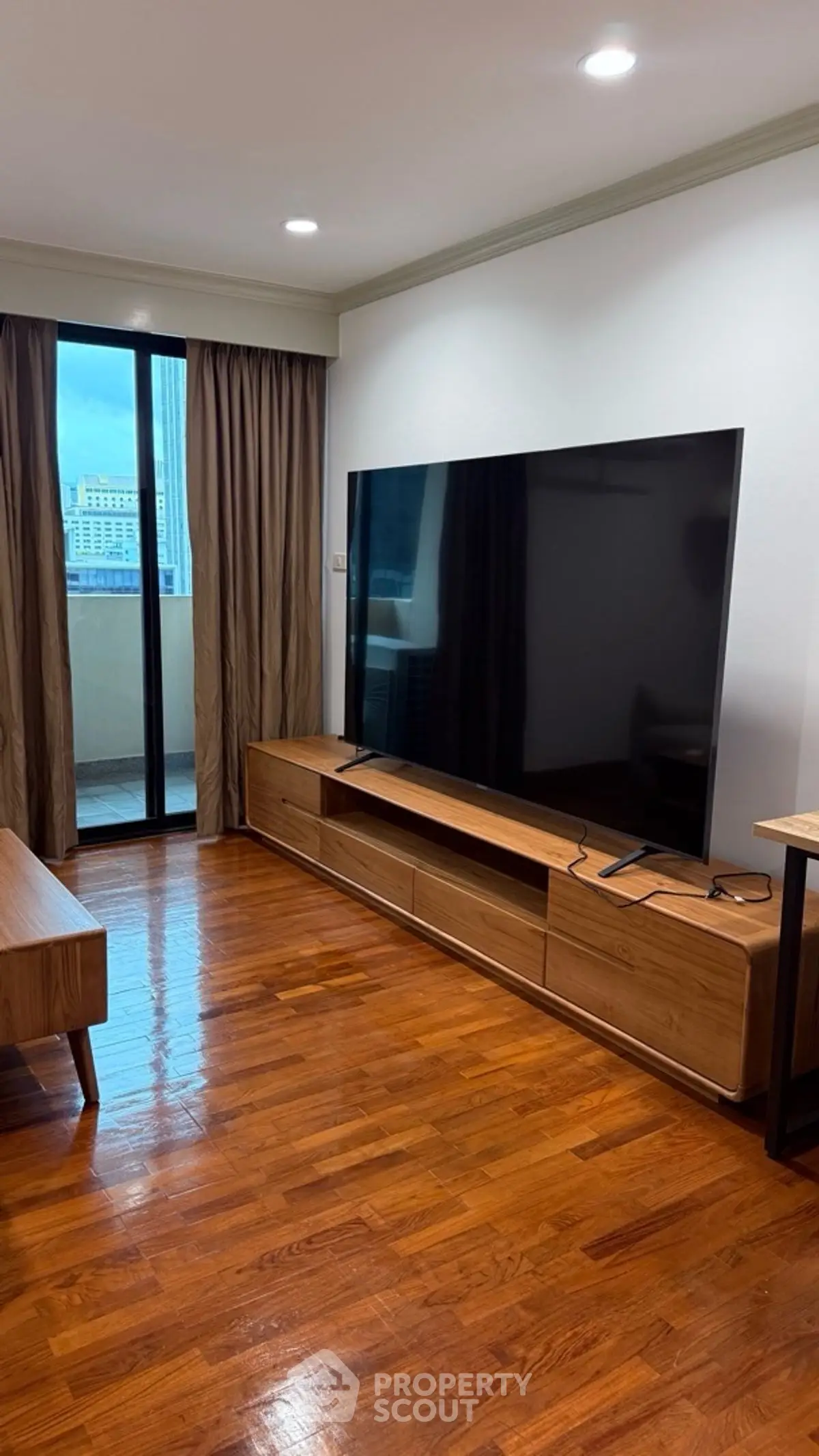 Spacious living room with large TV and balcony access in modern apartment