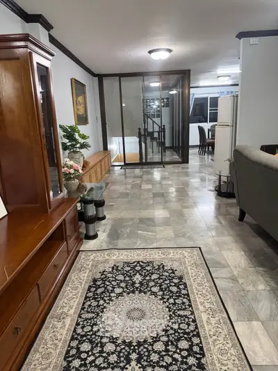 Spacious living area with elegant decor and marble flooring, featuring a cozy seating arrangement and stylish furnishings.
