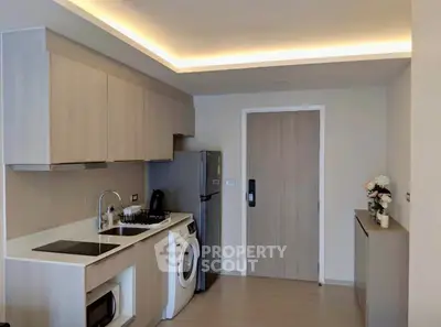Modern kitchen with sleek cabinetry, washing machine, and gas stove in a stylish apartment.